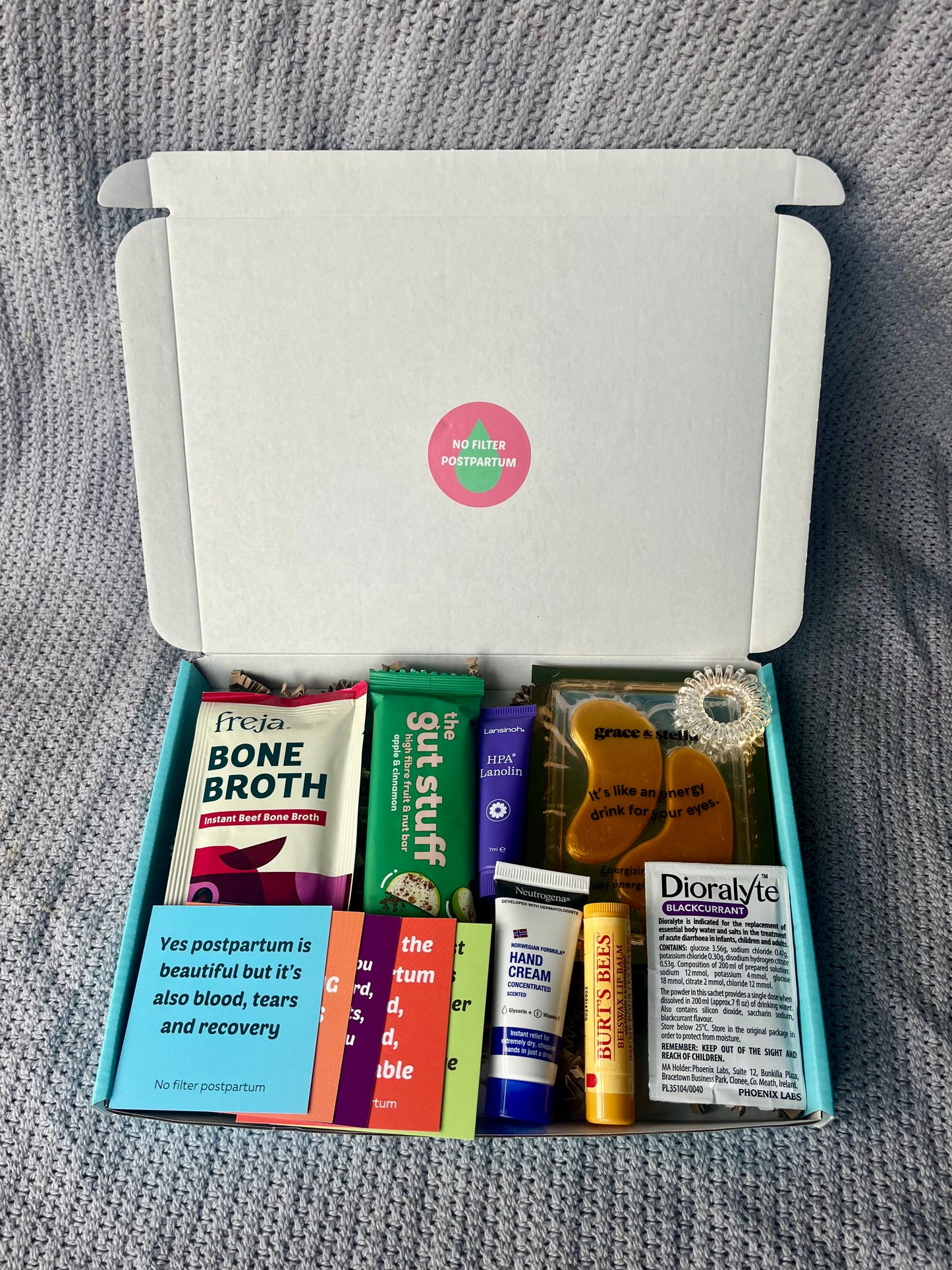 Open box containing various health and wellness products on a gray textured background