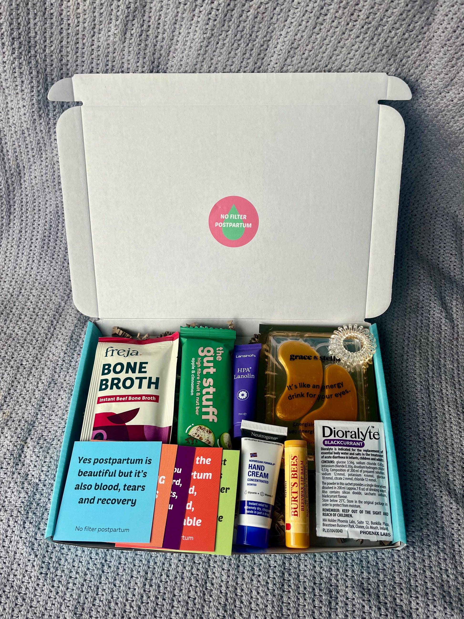 Open box containing various health and wellness products on a gray textured background